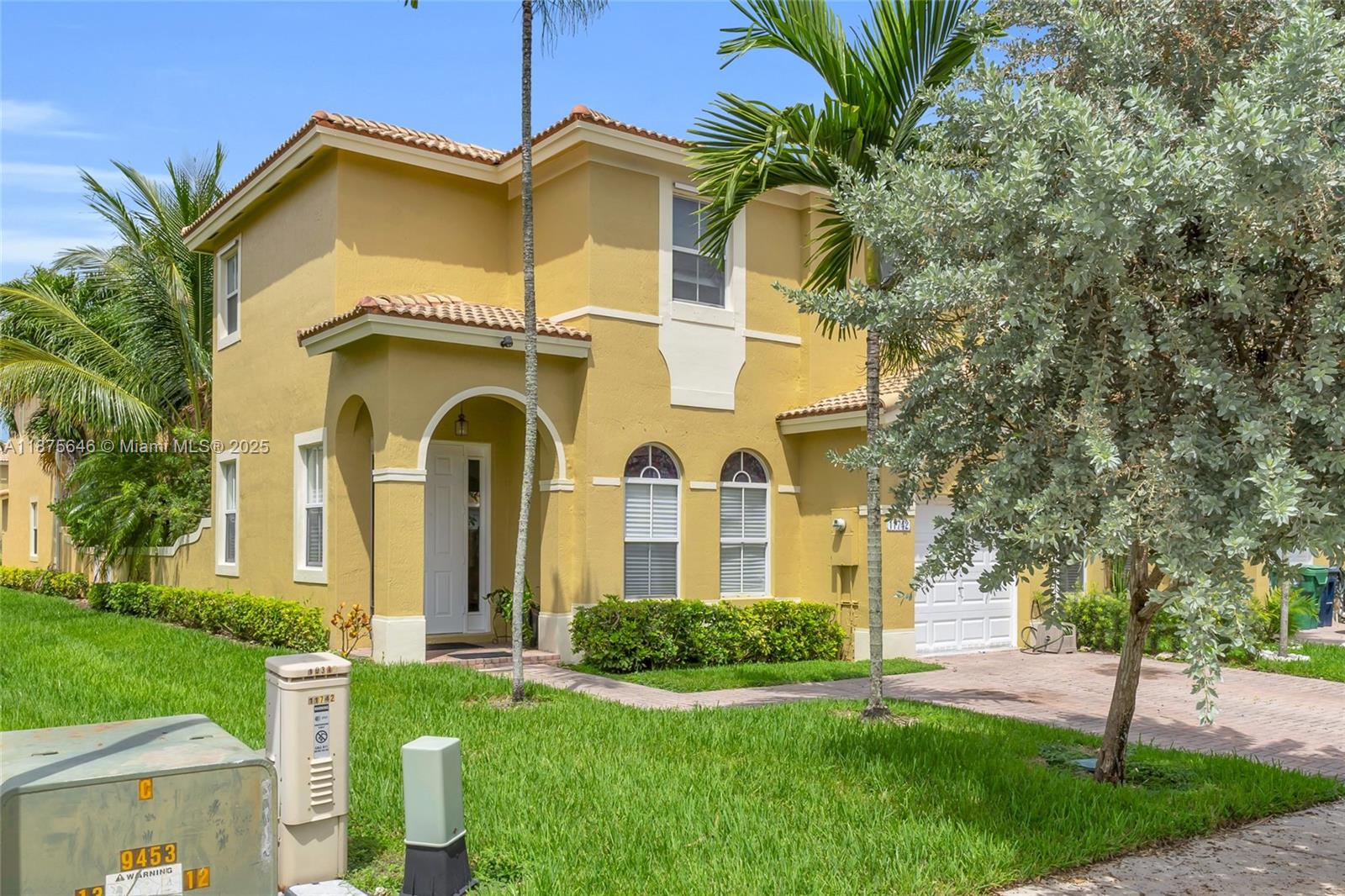 A two-story yellow stucco house with a tiled roof, arched entryway, and a paved driveway — 11742 SW 137th Pl, Miami FL 33186, MIAMI, FL