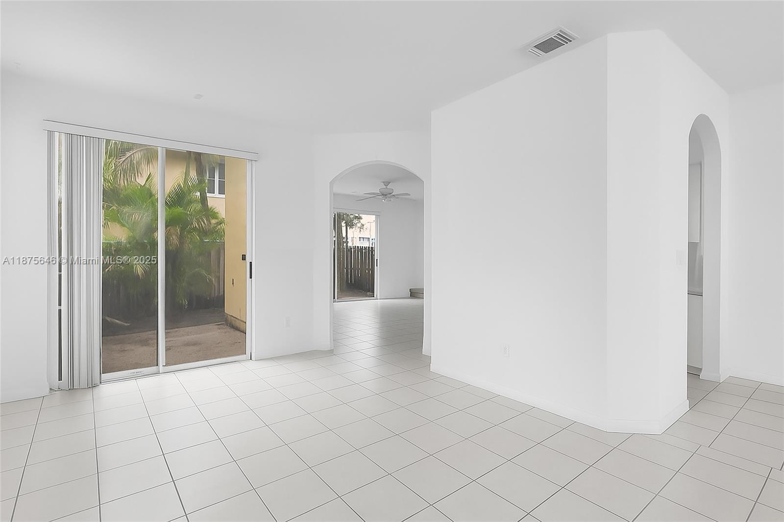 A bright, empty room features white walls, light-colored tile flooring, and sliding glass patio doors — 11742 SW 137th Pl, Miami FL 33186, MIAMI, FL