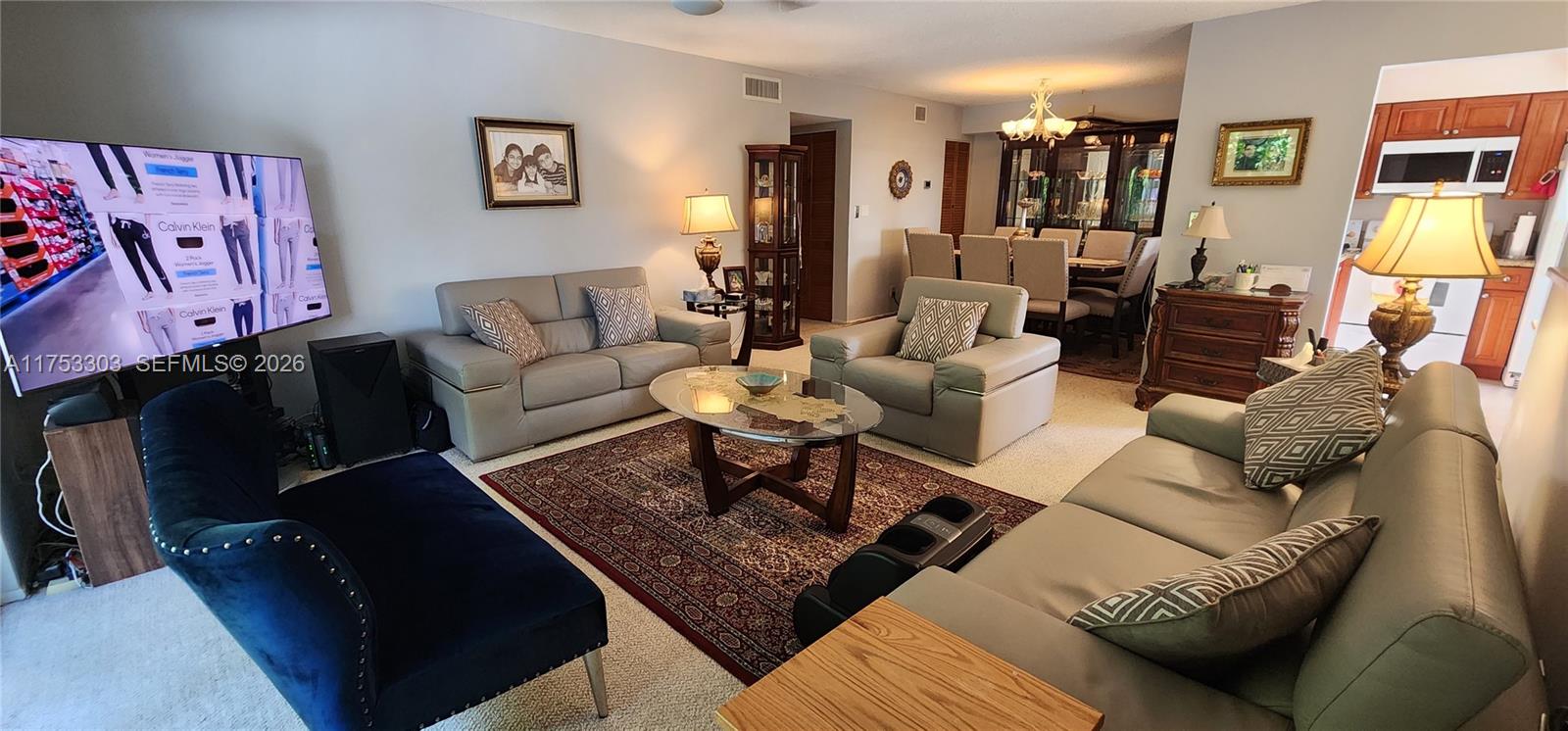 A living room with light-colored sofas, a patterned area rug, and an adjacent dining area — 111 Gardens Dr # 203, Pompano Beach FL 33069, POMPANO BEACH, FL