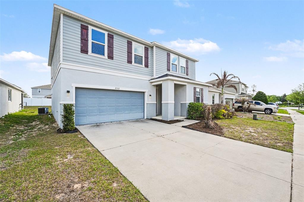 A two-story house with light blue siding, a two-car garage, and a concrete driveway — 2312 BISCOTTO CIRCLE, DAVENPORT, FL