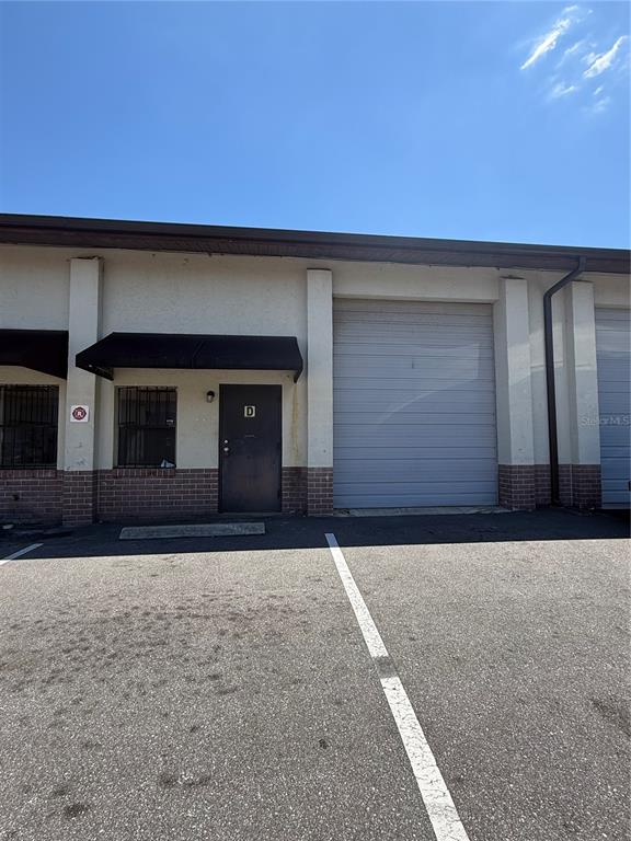 An exterior view of a commercial building unit with a metal roll-up door and entrance — 3892 NE 40TH PLACE UNIT D, OCALA, FL