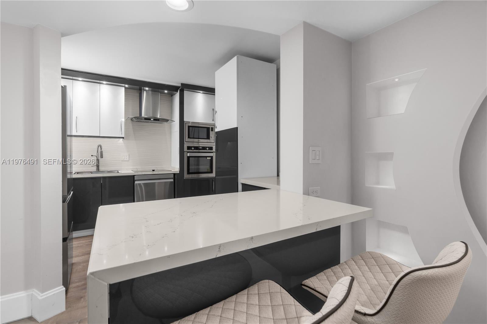 A modern kitchen features white upper cabinets, dark lower cabinets, and a white quartz island — 3730 Inverrary Dr # 2H, Lauderhill FL 33319, LAUDERHILL, FL