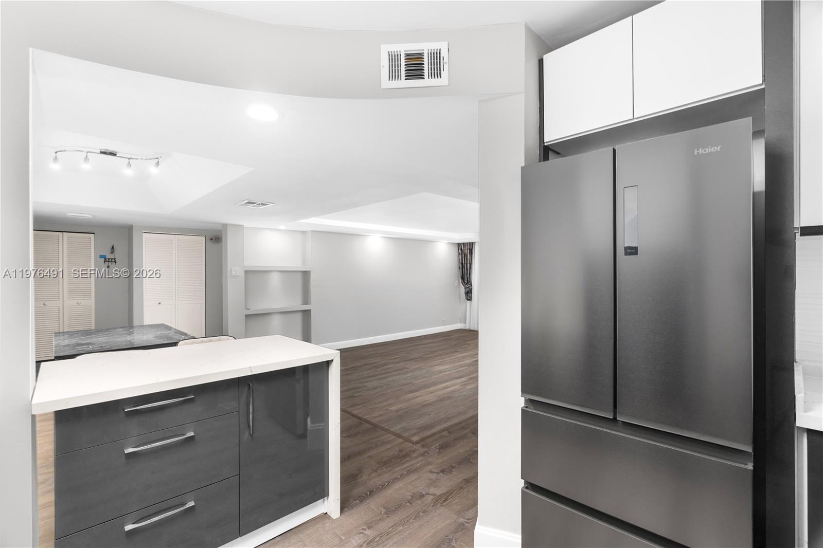 A kitchen with dark grey cabinets and a stainless steel refrigerator overlooks an open living area — 3730 Inverrary Dr # 2H, Lauderhill FL 33319, LAUDERHILL, FL