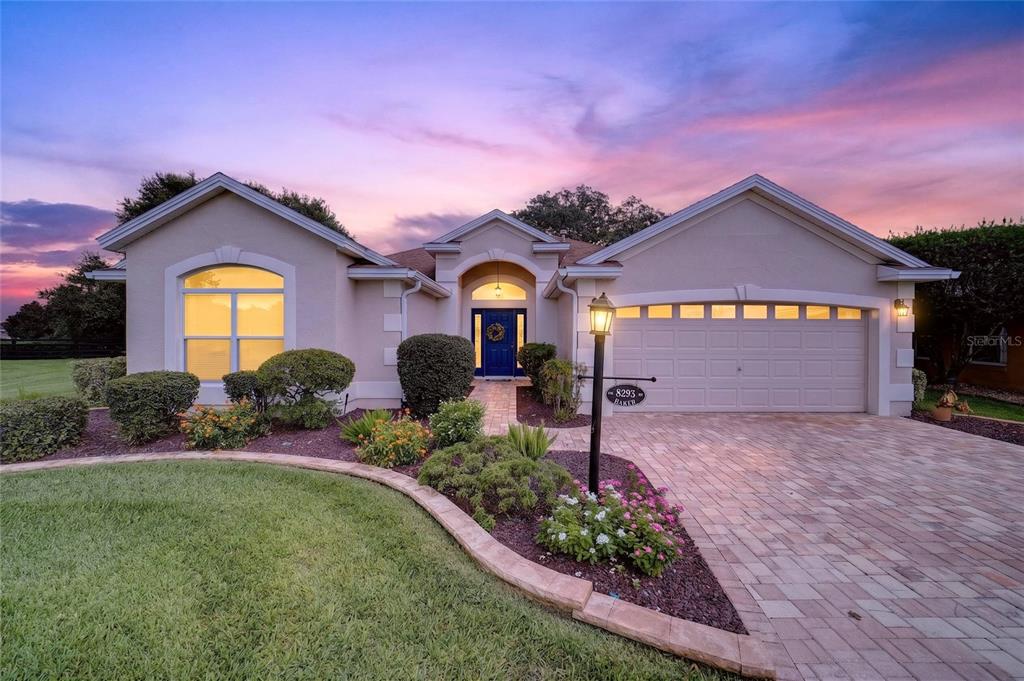 A single-story house with a beige stucco exterior, a blue front door, and a driveway — 8293 SE 176TH LAWSON LOOP, THE VILLAGES, FL