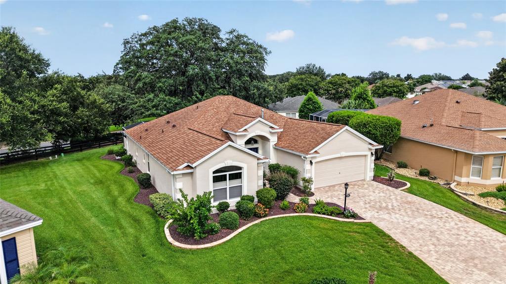 An aerial view of a single-story suburban house with a paved driveway and green lawn — 8293 SE 176TH LAWSON LOOP, THE VILLAGES, FL