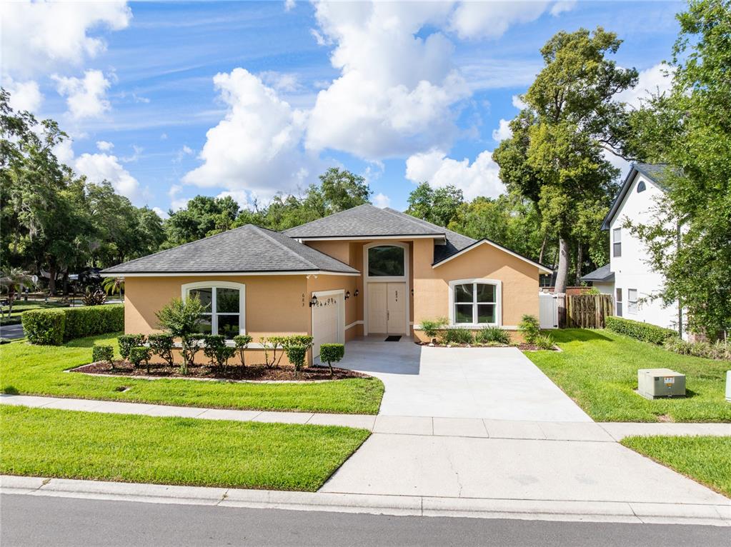 A tan, single-story suburban house with a concrete driveway and a gray shingled roof — 683 OAK HOLLOW WAY, ALTAMONTE SPRINGS, FL