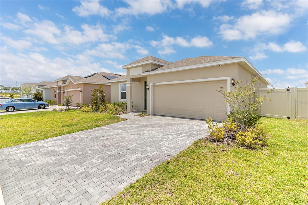 A single-story suburban house with a beige exterior, a two-car garage, and a paved driveway — 1559 GARDINER STREET, HAINES CITY, FL