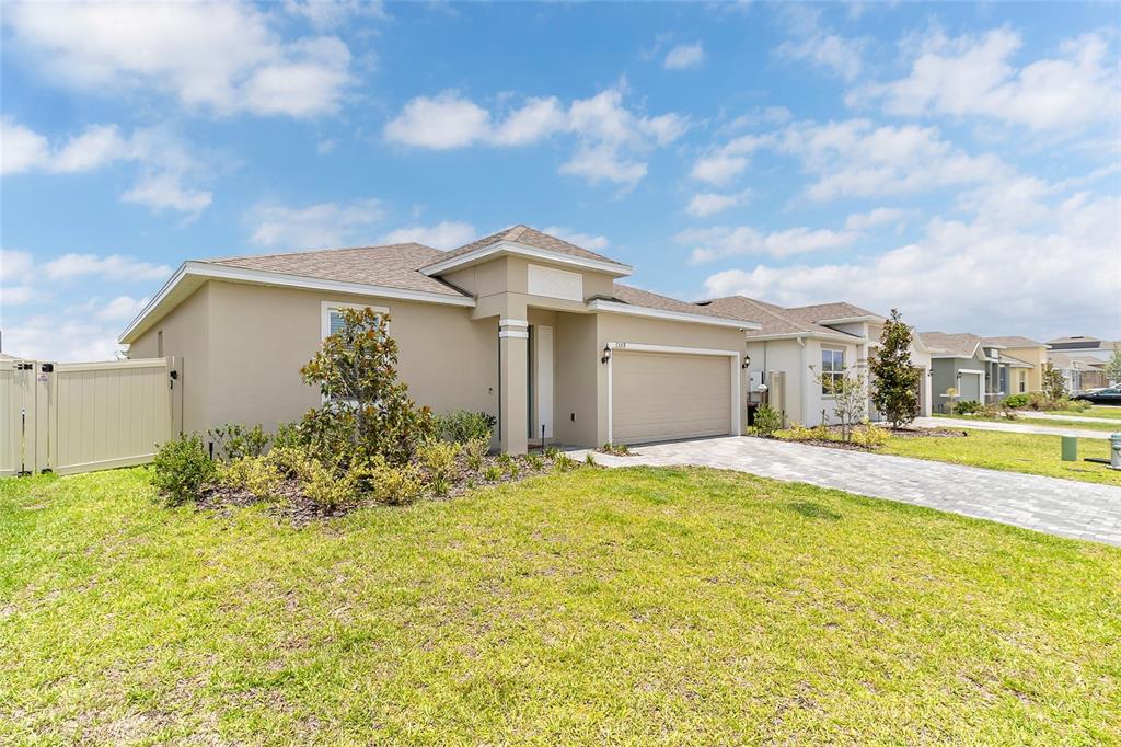 A single-story house with a beige stucco exterior, a two-car garage, and a paved driveway — 1559 GARDINER STREET, HAINES CITY, FL