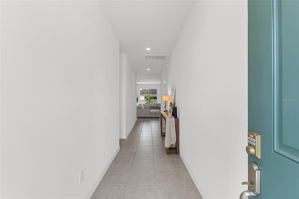 A tiled hallway leads from a teal front door toward a living area with furniture — 1559 GARDINER STREET, HAINES CITY, FL
