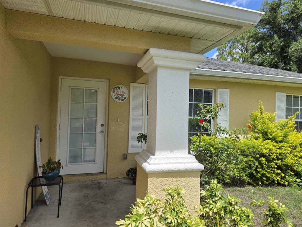 A front porch with a white door, a decorative sign, and a stucco column — 3529 SUNSHINE BOULEVARD, LEHIGH ACRES, FL