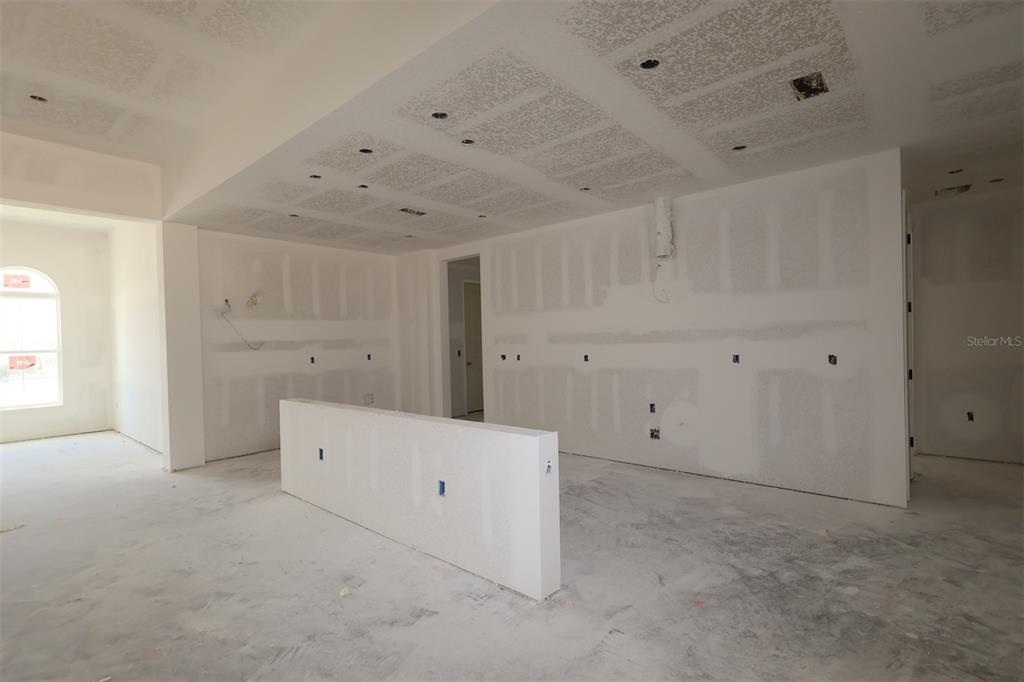 A modern kitchen features white cabinetry, a large island with a sink, and stainless appliances — 3254 WOLF LAKE AVENUE, APOPKA, FL