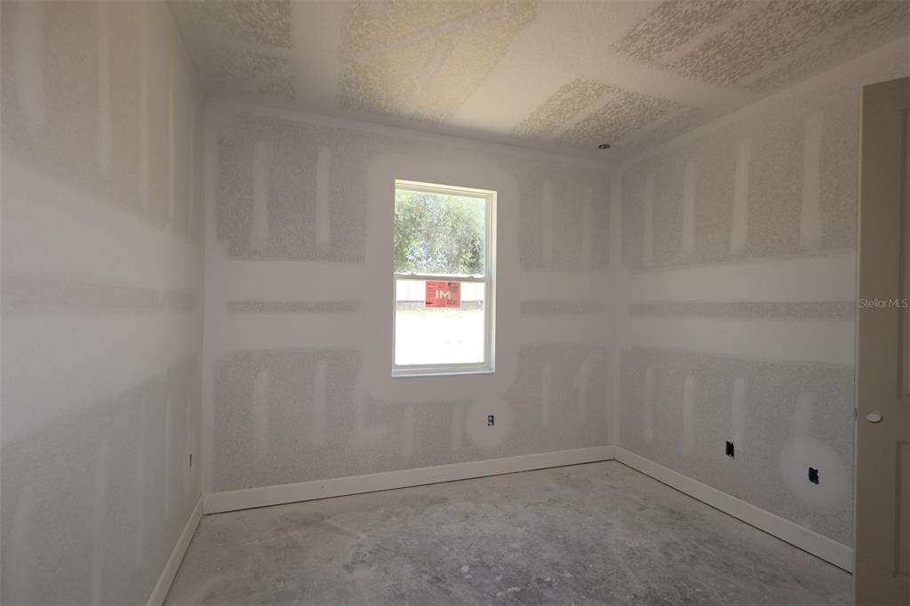 An open-concept kitchen and living area feature light wood flooring, white cabinetry, and sliding doors — 3254 WOLF LAKE AVENUE, APOPKA, FL