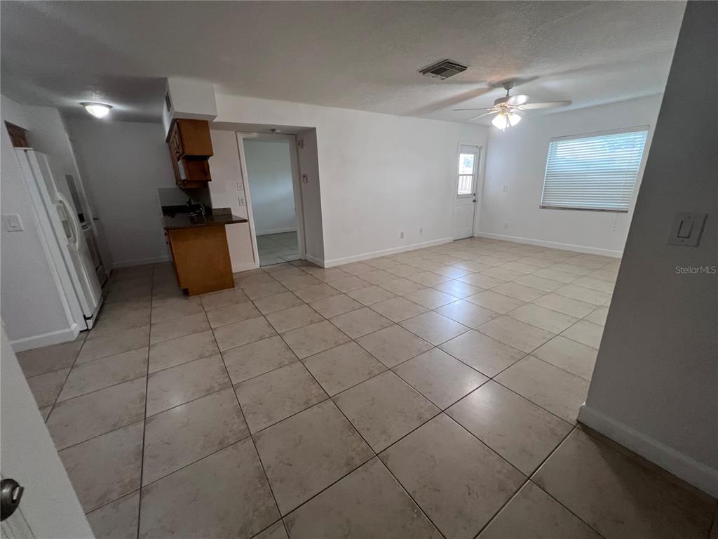 A tiled living area features a ceiling fan, a doorway, and an adjacent kitchen space — 226 THORN TREE PLACE UNIT 226, BRANDON, FL