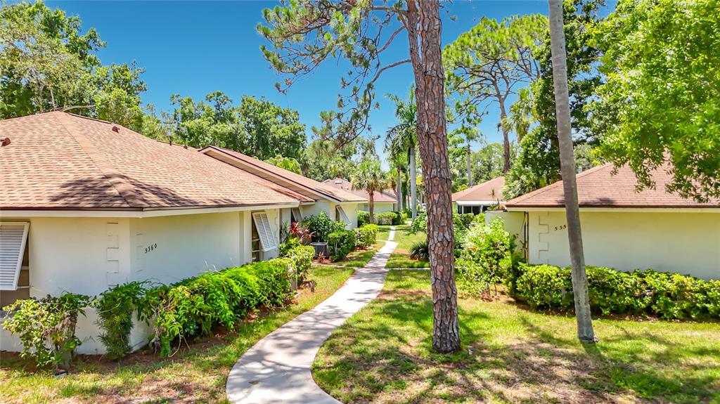 A sidewalk leads between two single-story residential buildings surrounded by trees and landscaping — 5354 ROYAL PALM AVENUE UNIT 5354, SARASOTA, FL