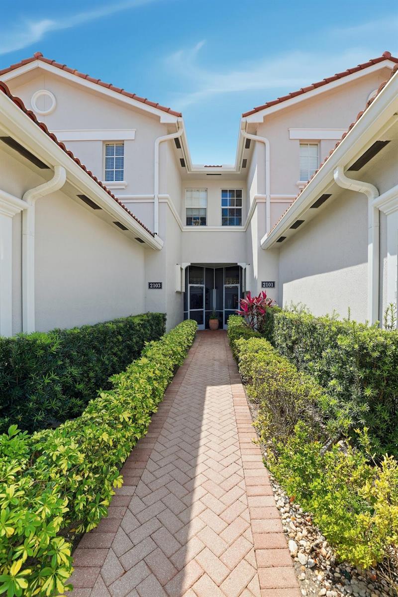 A brick walkway leads to the shared entrance of two residential units with beige siding — 2101 Wingate Bend, Wellington FL 33414, WELLINGTON, FL