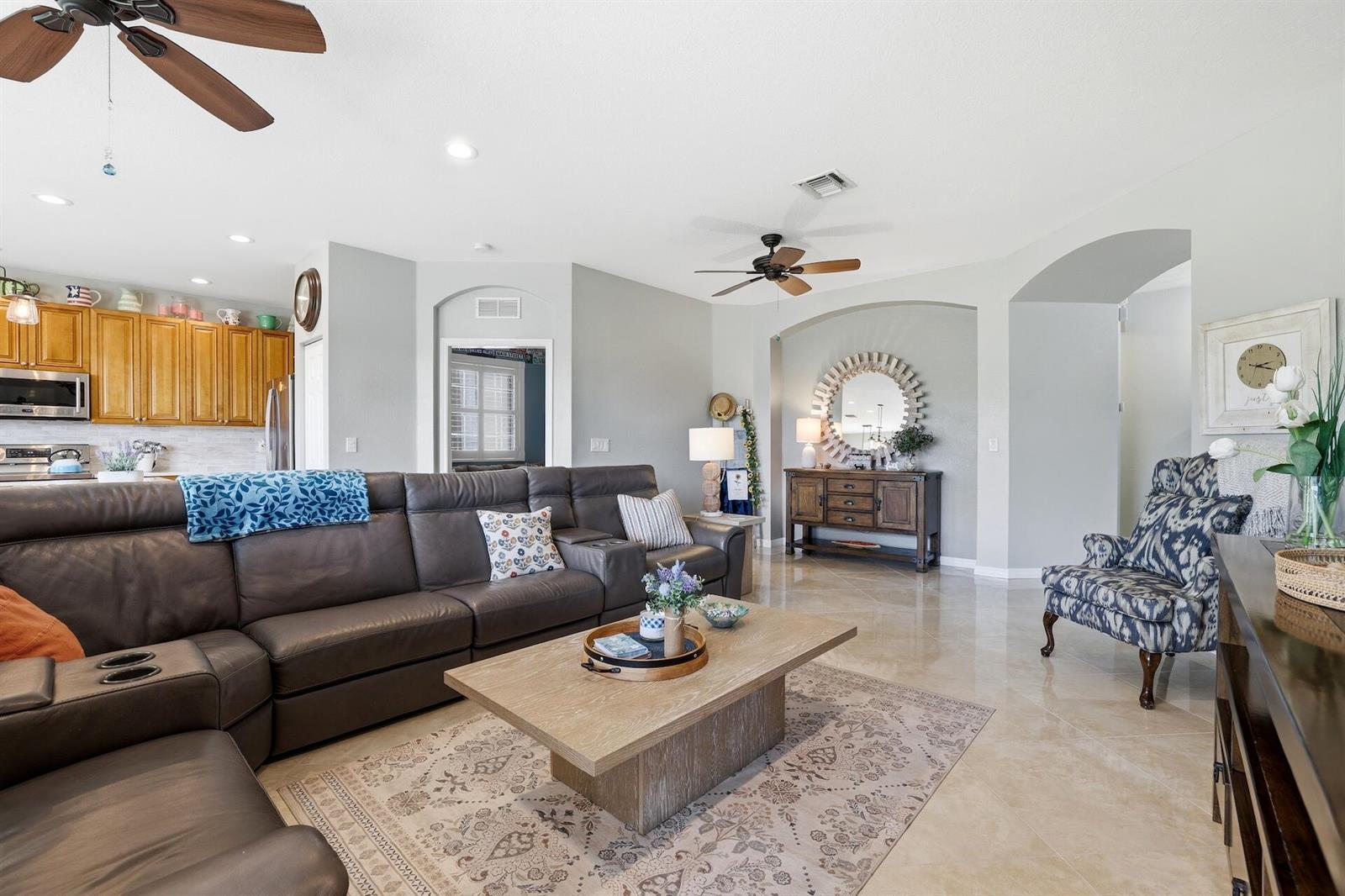 A living room features a large leather sectional, a wooden coffee table, and tile flooring — 2101 Wingate Bend, Wellington FL 33414, WELLINGTON, FL
