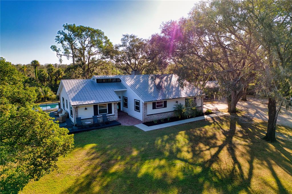 An aerial view of a white house with a metal roof and brick accents — 5310 JIM DAVIS ROAD, PARRISH, FL