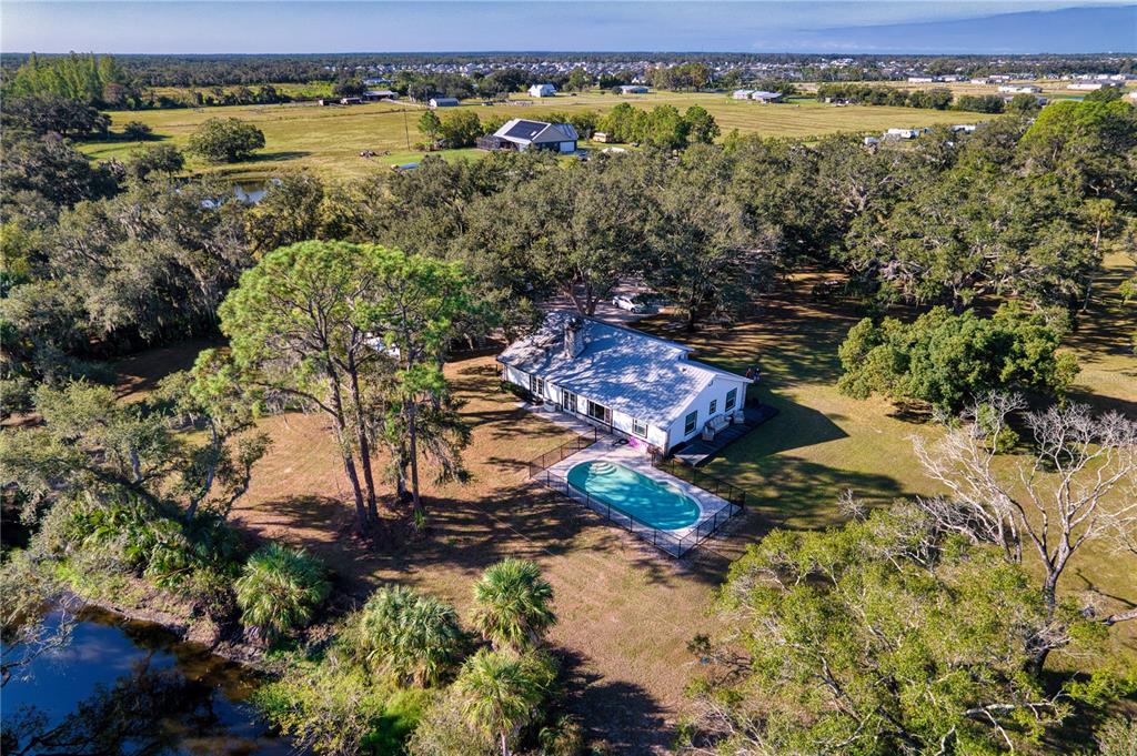 An aerial view shows a white house with a metal roof and a fenced pool — 5310 JIM DAVIS ROAD, PARRISH, FL