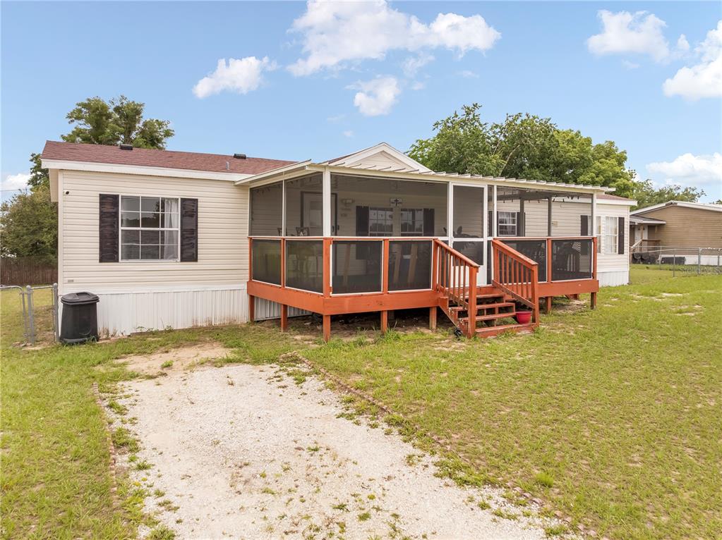 A single-story manufactured home features a screened-in wooden porch and a gravel driveway — 14205 SE 60TH AVENUE, SUMMERFIELD, FL