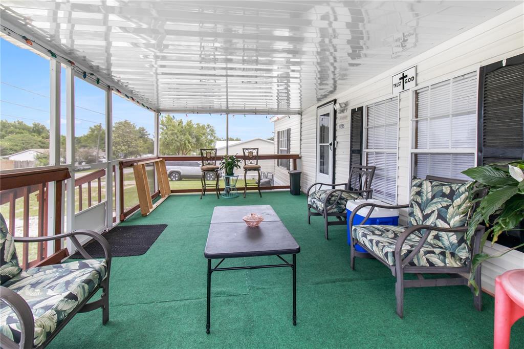A covered screened-in porch features green outdoor carpeting, patio furniture, and a metal ceiling — 14205 SE 60TH AVENUE, SUMMERFIELD, FL