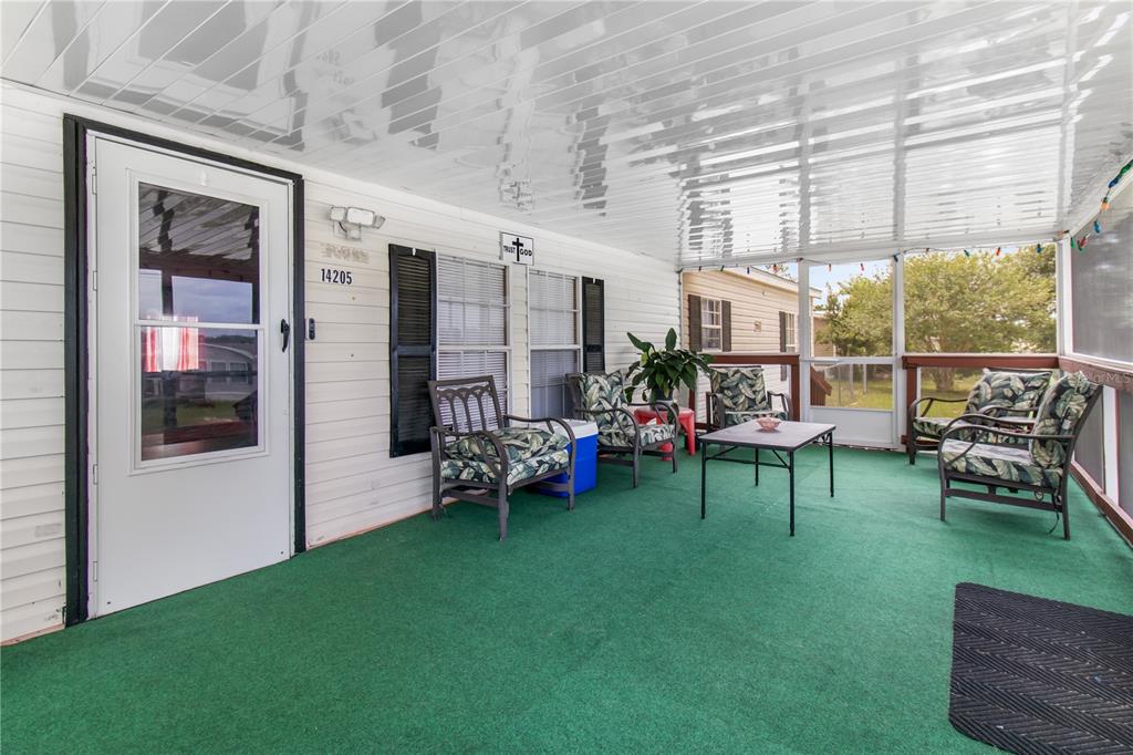 A screened-in porch features green carpeting, white siding, and several chairs around a small table — 14205 SE 60TH AVENUE, SUMMERFIELD, FL