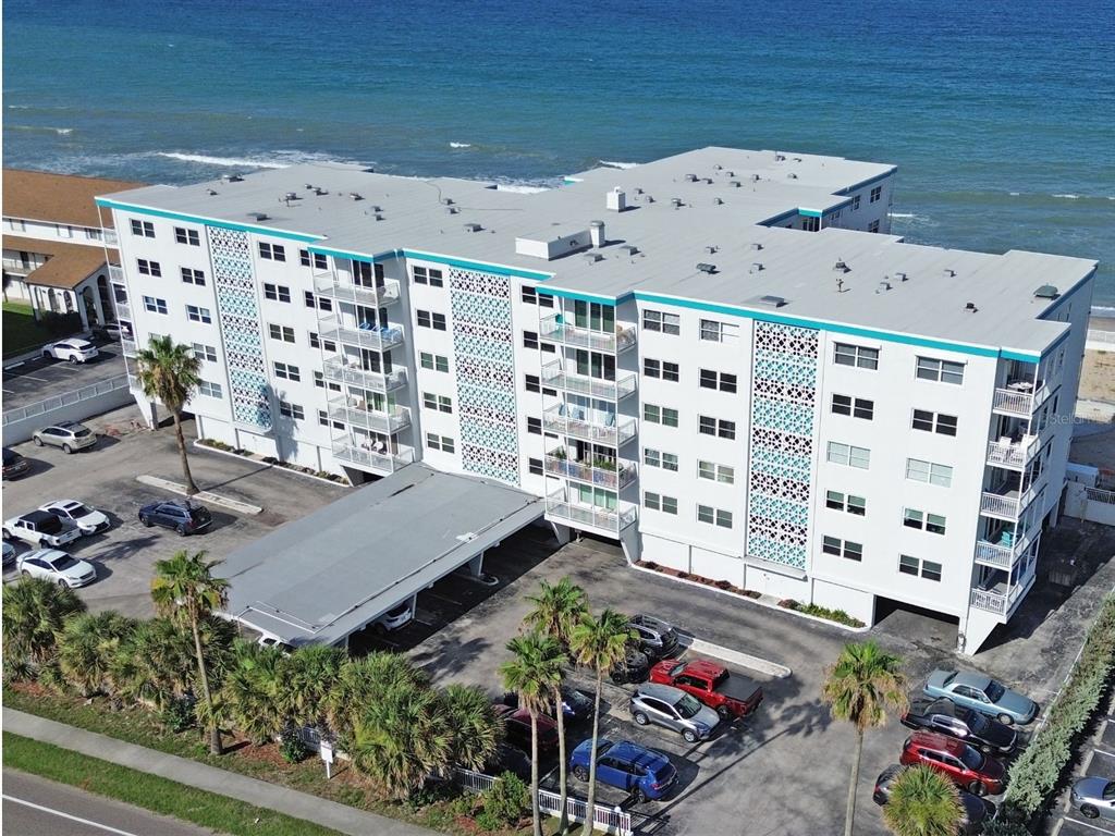 An aerial view of a multi-story white apartment building located directly on the beach — 205 HIGHWAY A1A #501 UNIT 501, SATELLITE BEACH, FL