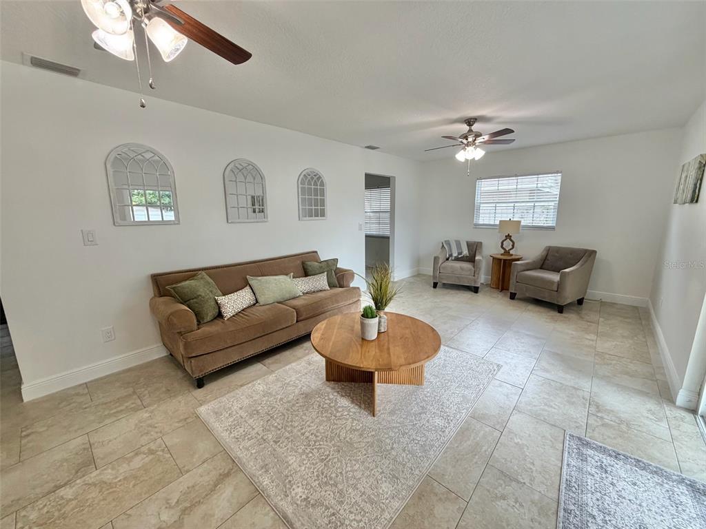 A living room features tile flooring, a brown sofa, two armchairs, and a round table — 6945 ORKNEY AVENUE N, ST PETERSBURG, FL