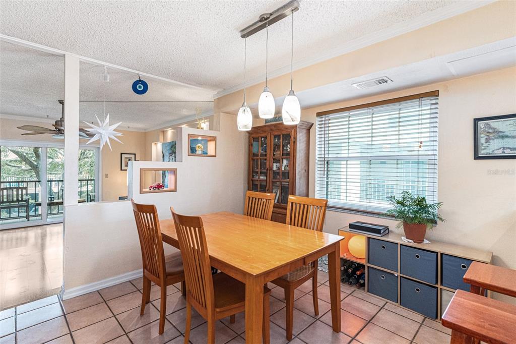 A dining room features a wooden table, four chairs, pendant lighting, and a storage unit — 12465 2ND STREET E UNIT 105B, TREASURE ISLAND, FL