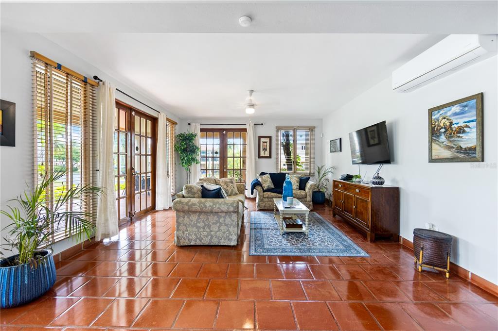 A living room features terracotta tile floors, two sofas, a television, and glass patio doors — E LAKESIDE VILLAS UNIT 1, VEGA ALTA, PR