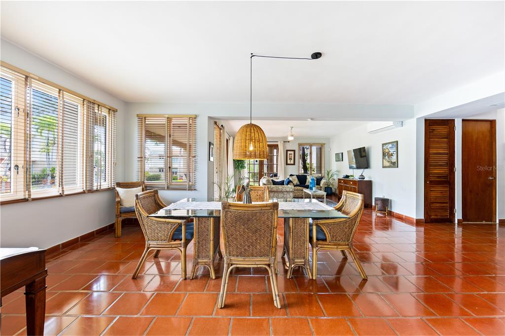 A dining area with a glass table and wicker chairs sits on terracotta tile floors — E LAKESIDE VILLAS UNIT 1, VEGA ALTA, PR