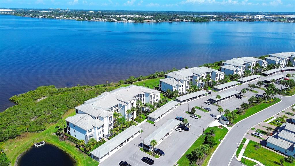An aerial view shows a multi-story apartment complex situated along a large body of water — 850 TIDEWATER SHORES LOOP UNIT 402, BRADENTON, FL