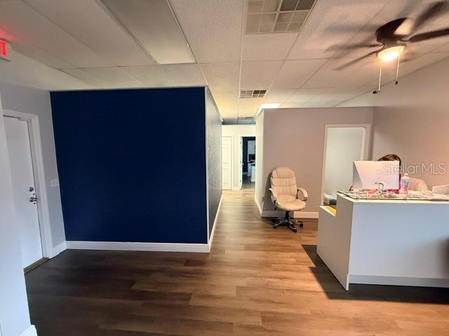 An office reception area features a dark blue accent wall, wood-look flooring, and a desk — 223 COMMONWEALTH AVENUE SW, POLK CITY, FL