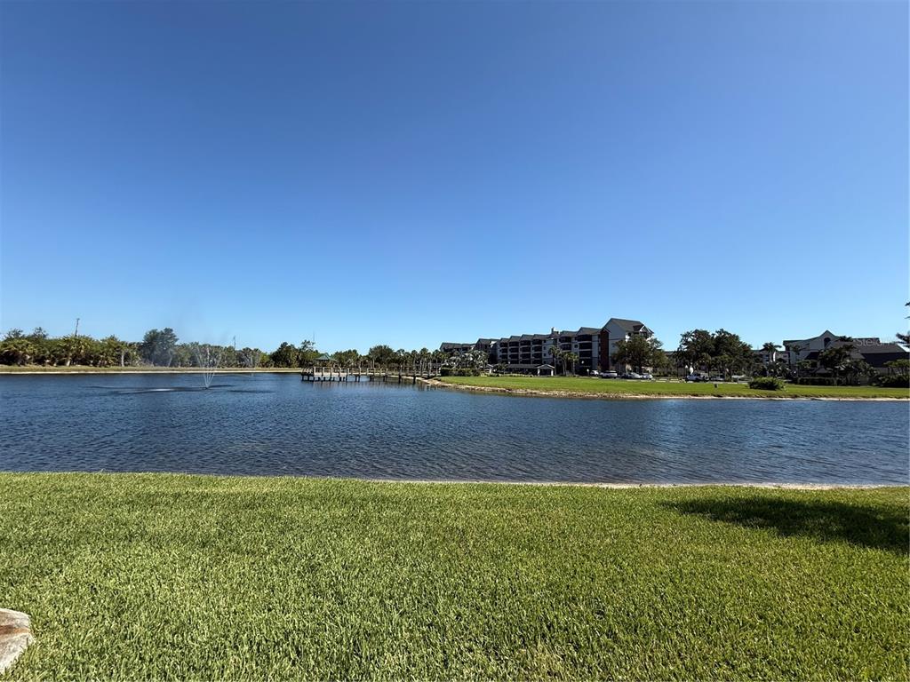 A view of a lake with a fountain and a wooden pier near apartment buildings — 23124 WESTCHESTER BOULEVARD, PUNTA GORDA, FL