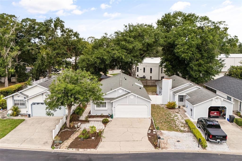 An aerial view of three suburban houses with light siding, driveways, and mature trees — 106 LAMPLIGHTER DRIVE, SANFORD, FL