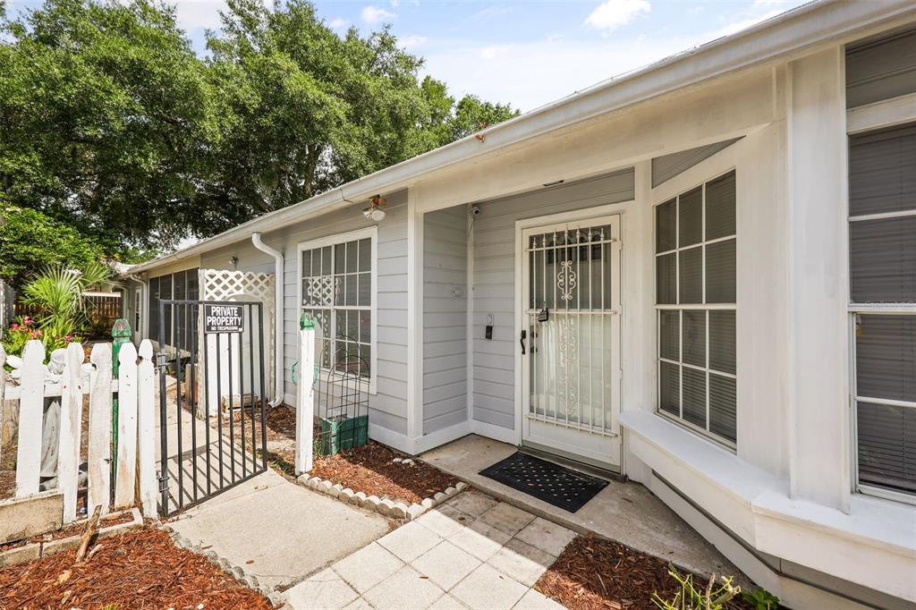 A light gray house exterior features a white security door, white picket fence, and walkway — 106 LAMPLIGHTER DRIVE, SANFORD, FL