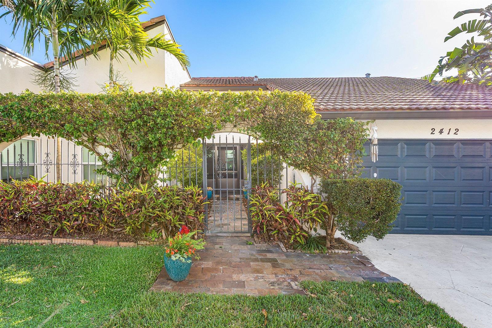 A gated stone walkway leads to the front entrance of a house with a garage — 2412 SW 23rd Cranbrook Drive, Boynton Beach FL 33436, BOYNTON BEACH, FL