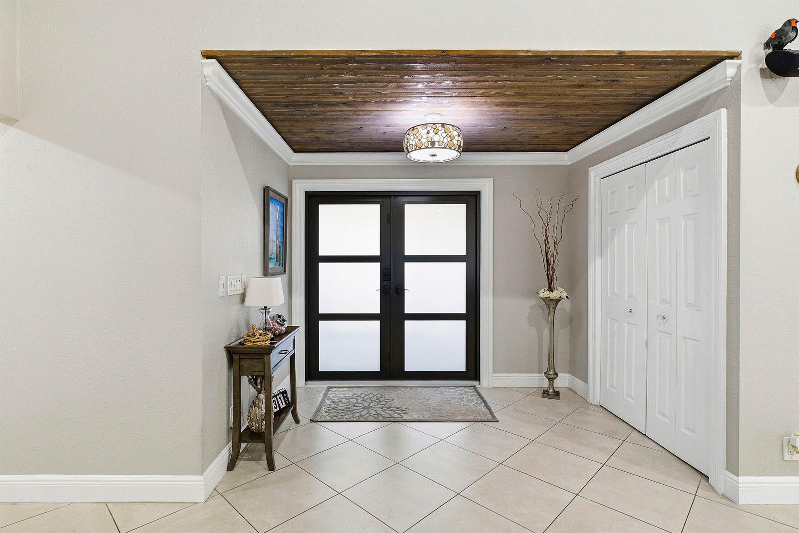 An entryway features a wood-paneled ceiling, double glass doors, and a tiled floor — 2412 SW 23rd Cranbrook Drive, Boynton Beach FL 33436, BOYNTON BEACH, FL