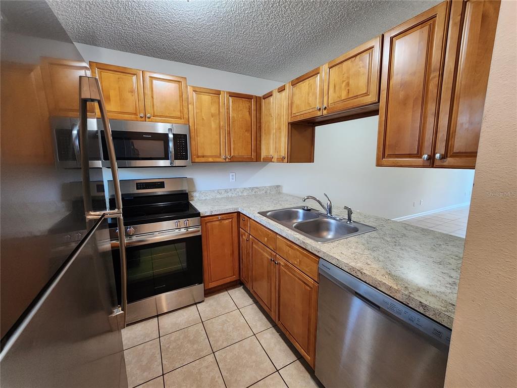A kitchen with wood cabinets, stainless steel appliances, and a light-colored countertop — 39132 COUNTY ROAD 54 UNIT 2152, ZEPHYRHILLS, FL