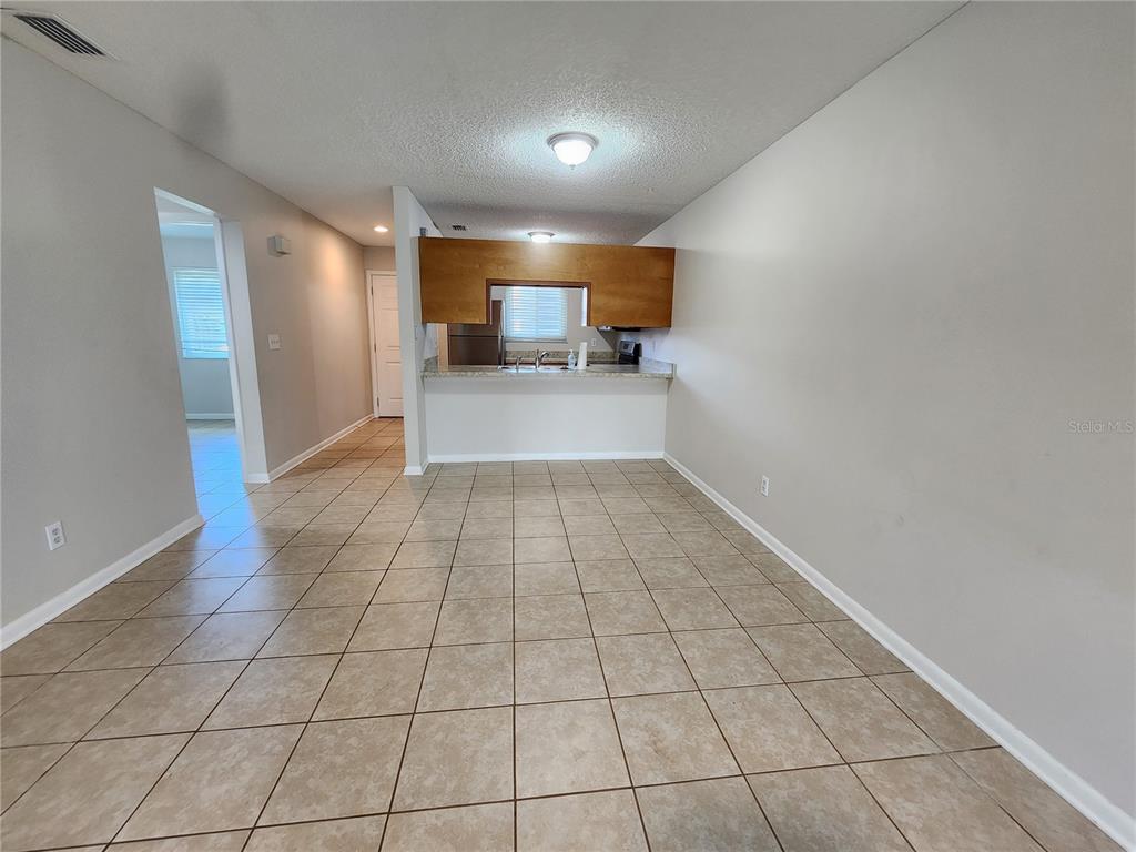 A dining area with tiled floors leads to a kitchen with a wooden pass-through window — 39132 COUNTY ROAD 54 UNIT 2152, ZEPHYRHILLS, FL