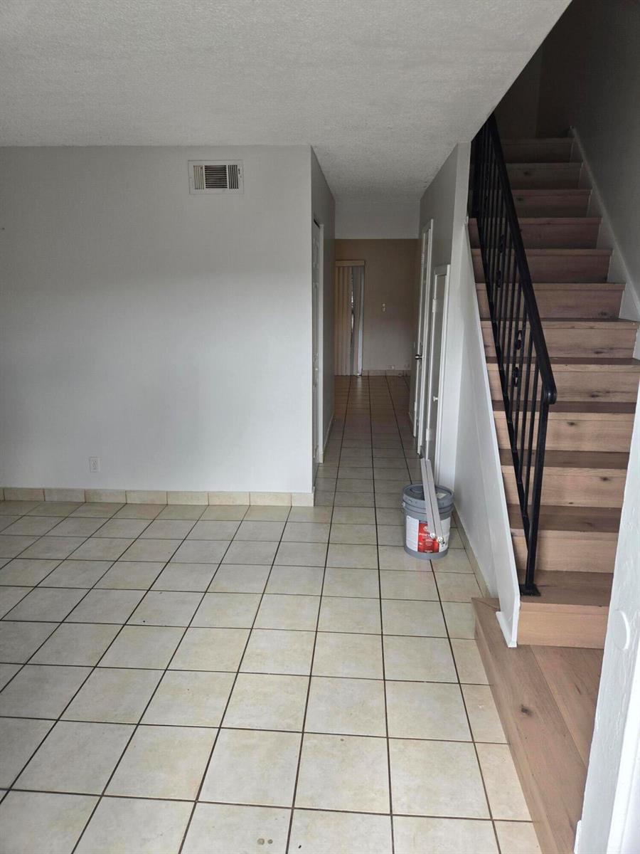 A room with light-colored floor tiles, a staircase with wooden treads, and a hallway — 3714 SW 60th Terrace # 28, Davie FL 33314, DAVIE, FL