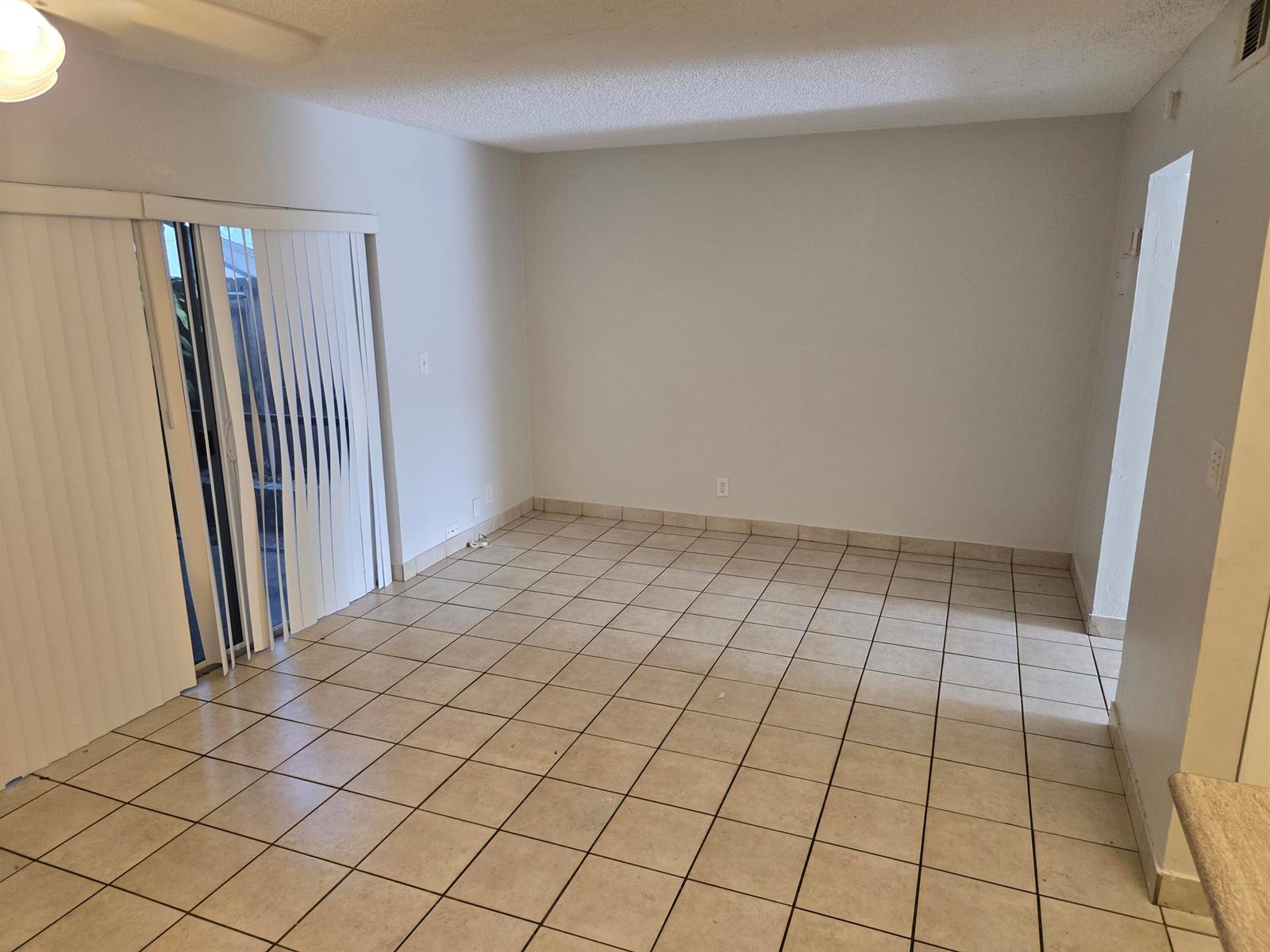 An empty room features light-colored tile flooring, white walls, and a sliding glass door — 3714 SW 60th Terrace # 28, Davie FL 33314, DAVIE, FL