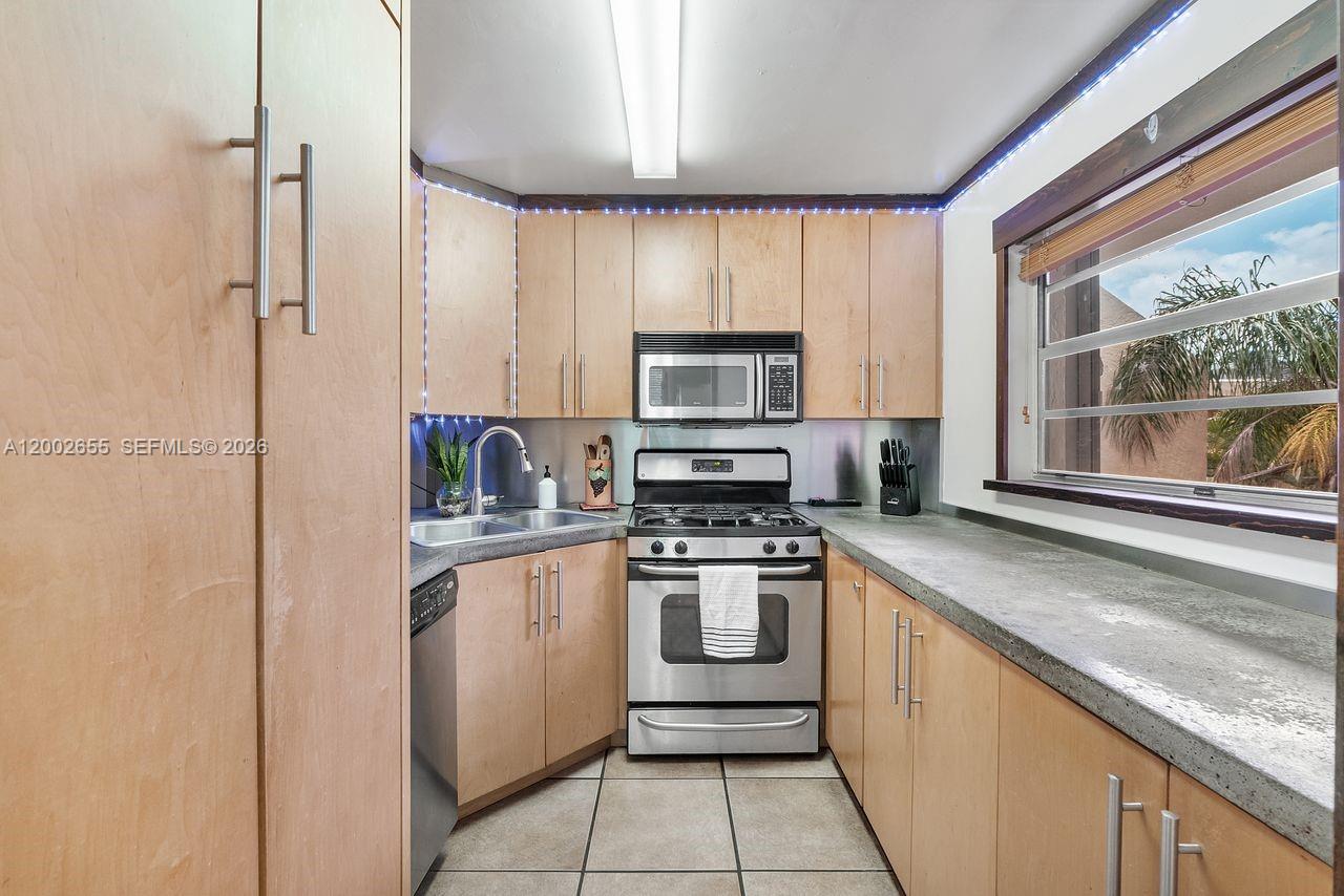 A kitchen features light wood cabinets, stainless steel appliances, and a window with exterior views — 13100 SW 92nd Ave, Miami FL 33176, MIAMI, FL