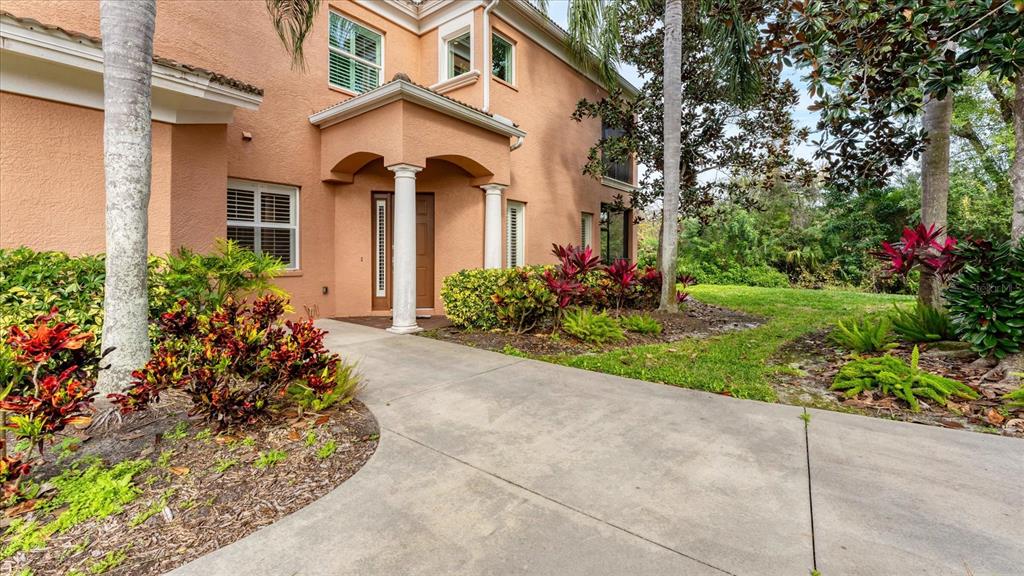 A concrete walkway leads to the entrance of a two-story peach-colored stucco house — 5433 46TH COURT W, BRADENTON, FL
