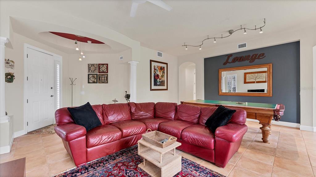 A living room features a red leather sectional, a pool table, and tile flooring — 5433 46TH COURT W, BRADENTON, FL