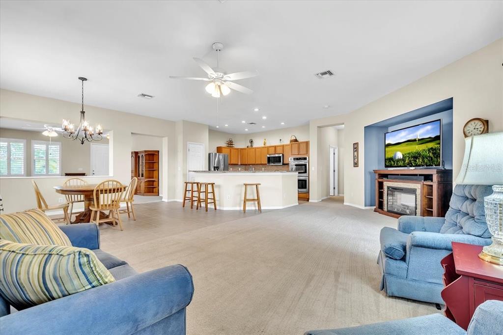 An open-concept living area features a kitchen with wooden cabinets, a dining space, and carpet — 12933 SW PEMBROKE CIRCLE S, LAKE SUZY, FL