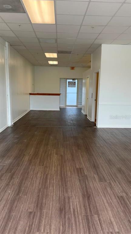 An empty commercial space features wood-look flooring, a drop ceiling, and a rear service counter — 1412 W WATERS AVENUE UNIT 202, TAMPA, FL