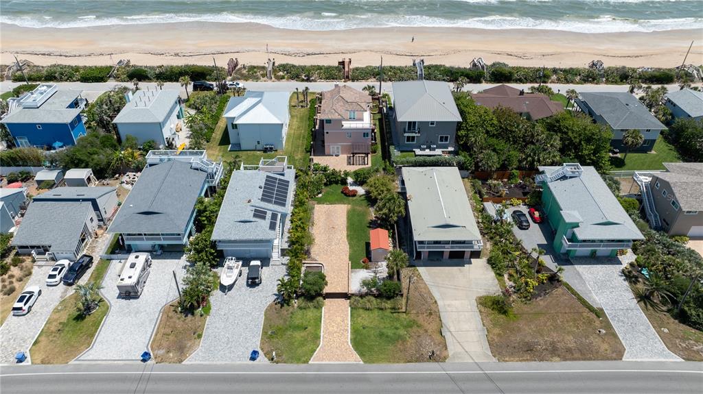 An aerial view shows a coastal neighborhood with houses situated between the ocean and wetlands — 6260 S ATLANTIC AVENUE, NEW SMYRNA BEACH, FL
