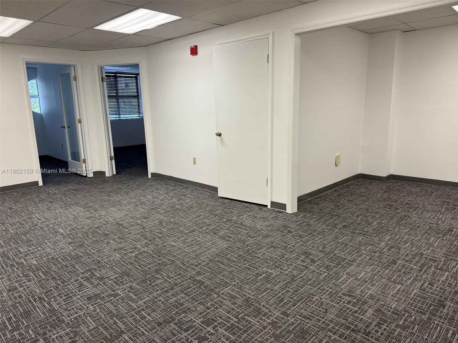 An empty office space features gray patterned carpet, white walls, and multiple doorways — 220 Miracle Mile, Coral Gables FL 33134, CORAL GABLES, FL