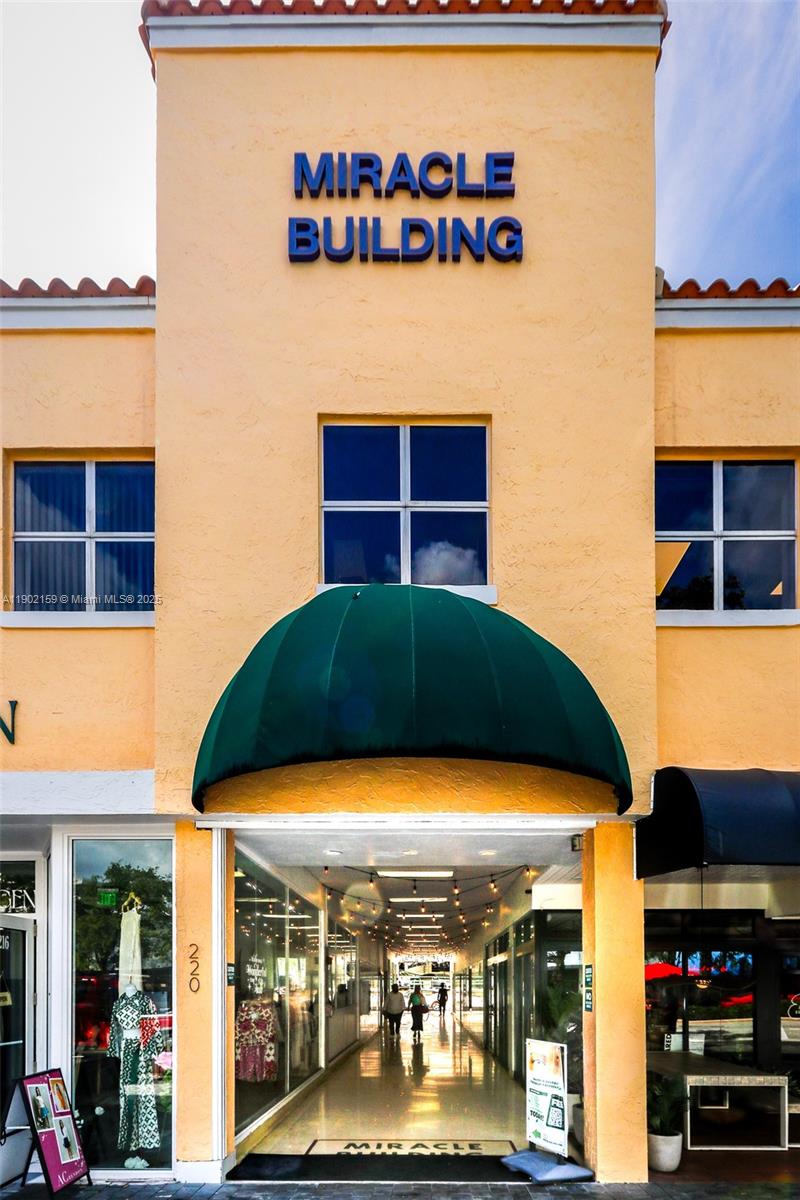 The exterior of the Miracle Building features a yellow facade with a green awning entrance — 220 Miracle Mile, Coral Gables FL 33134, CORAL GABLES, FL