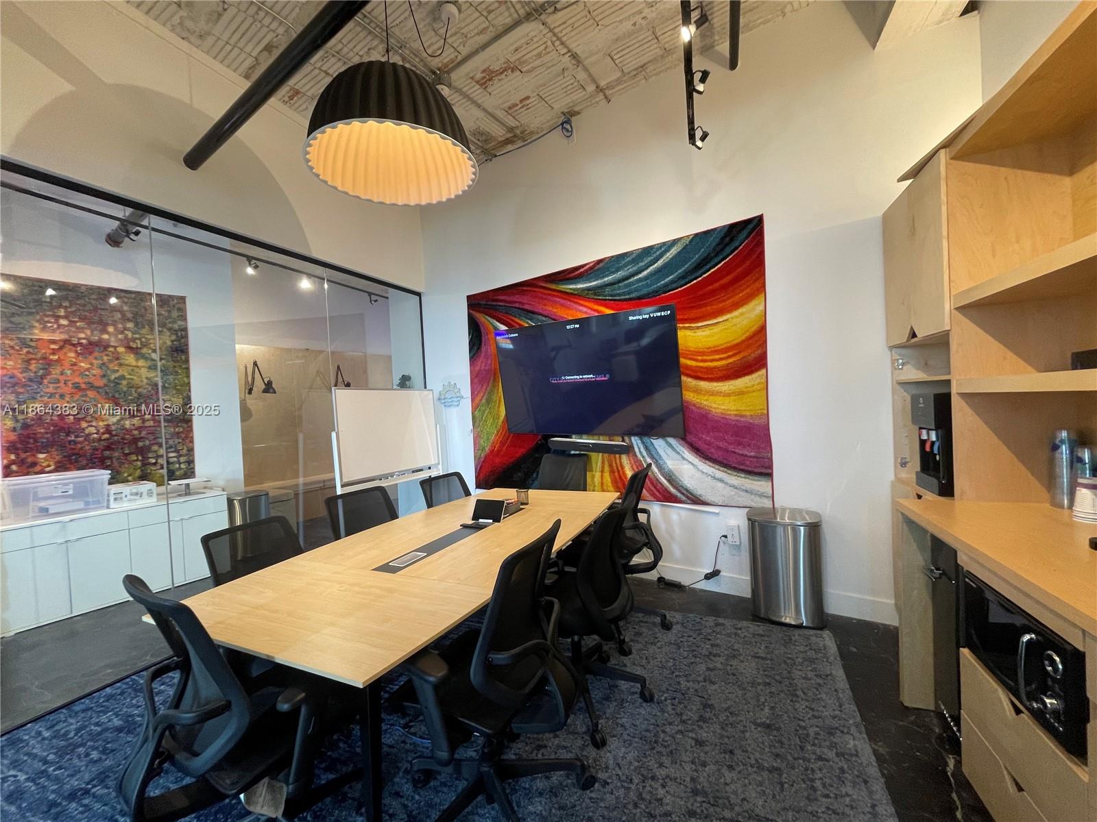 A modern conference room features a long wooden table, black chairs, and a wall-mounted television — 1900 NE Miami Ct, Miami FL 33132, MIAMI, FL